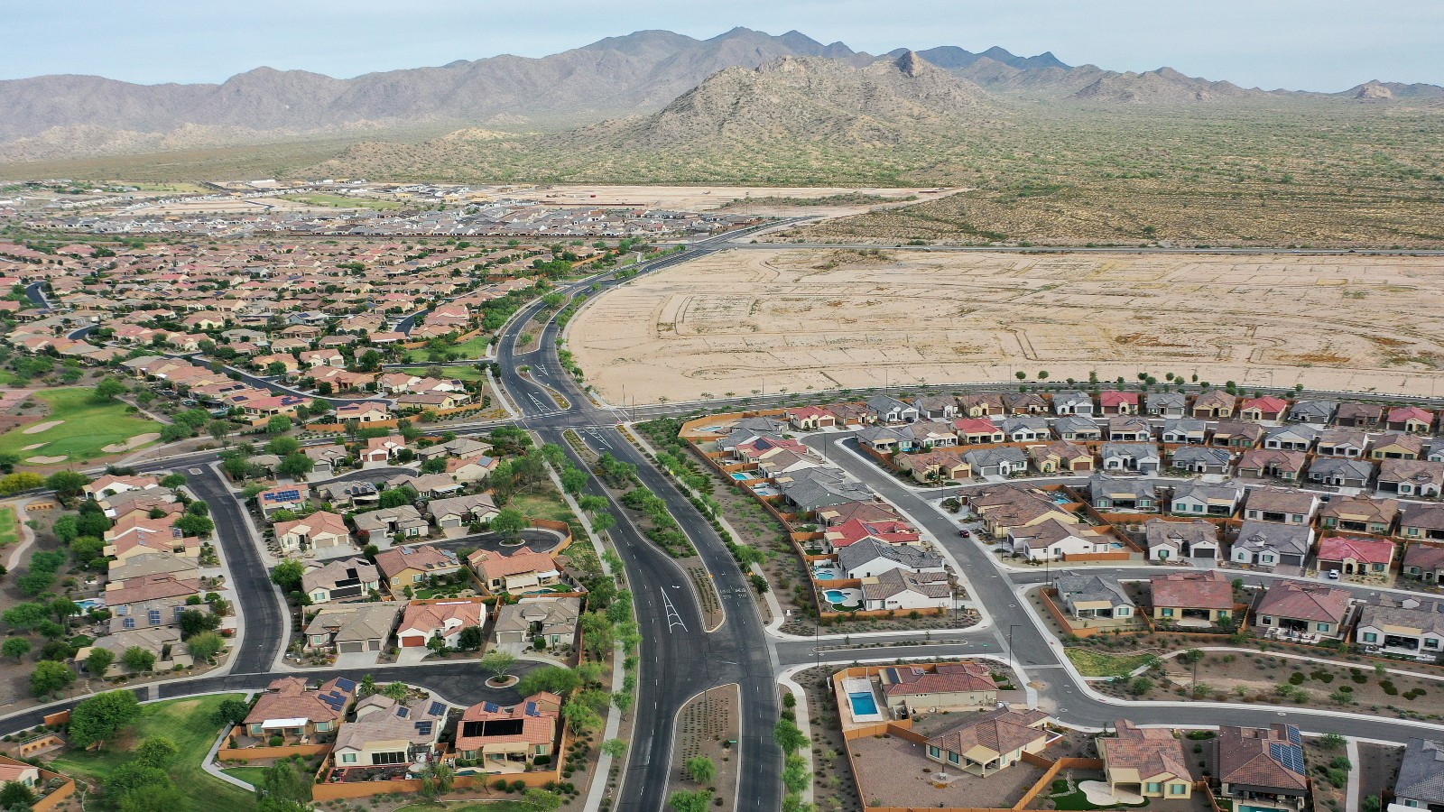 An aerial shot of a city at the foot of mountains and next to a slice of empty desert.