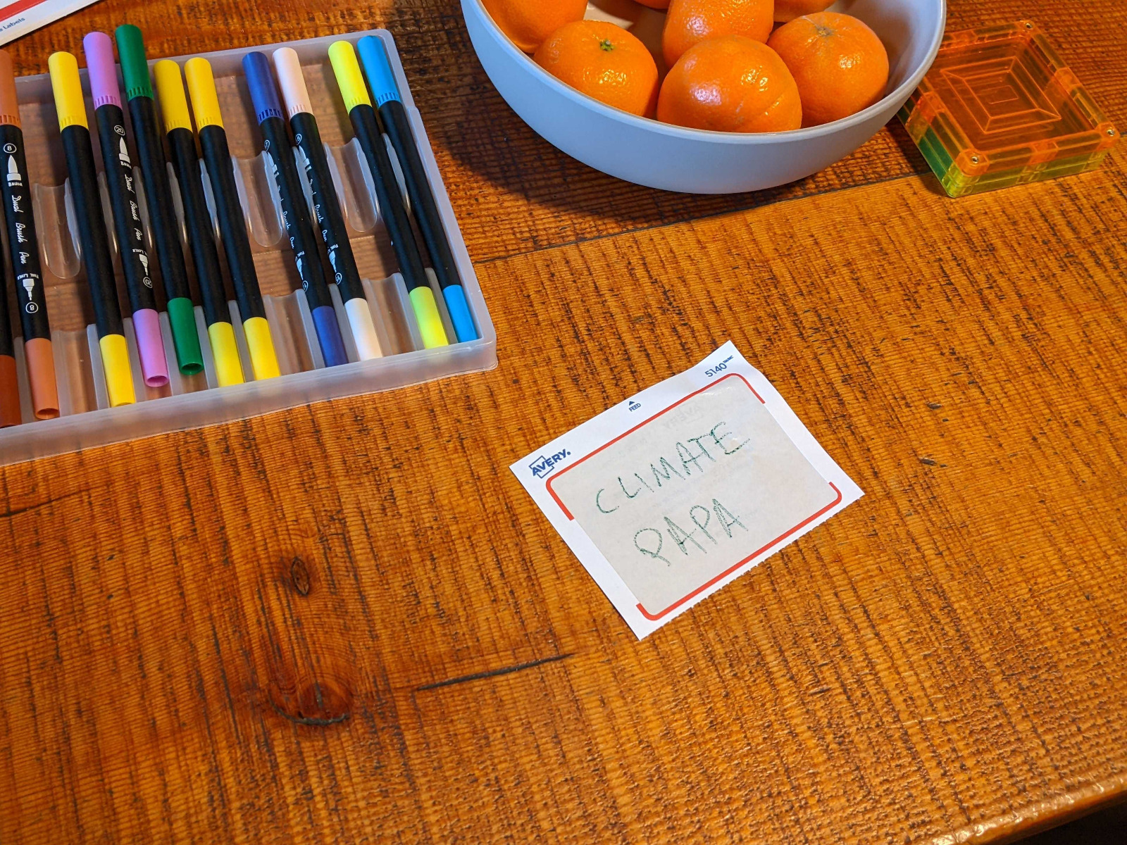 Photo of a table with markers, clementines, and a climate papa nametag
