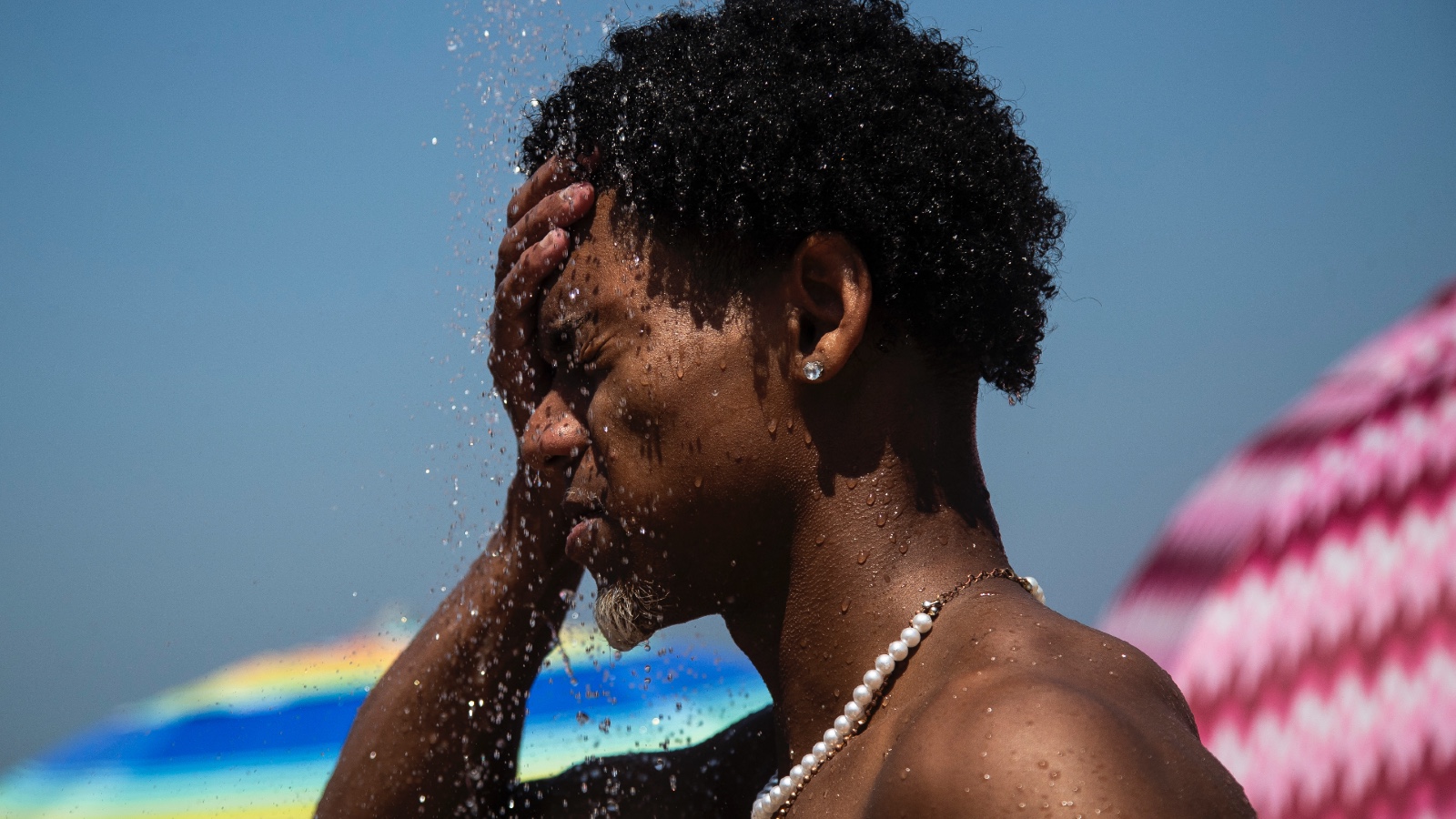 A person in Brazil splashes water on their face to cool off during a heat wave.