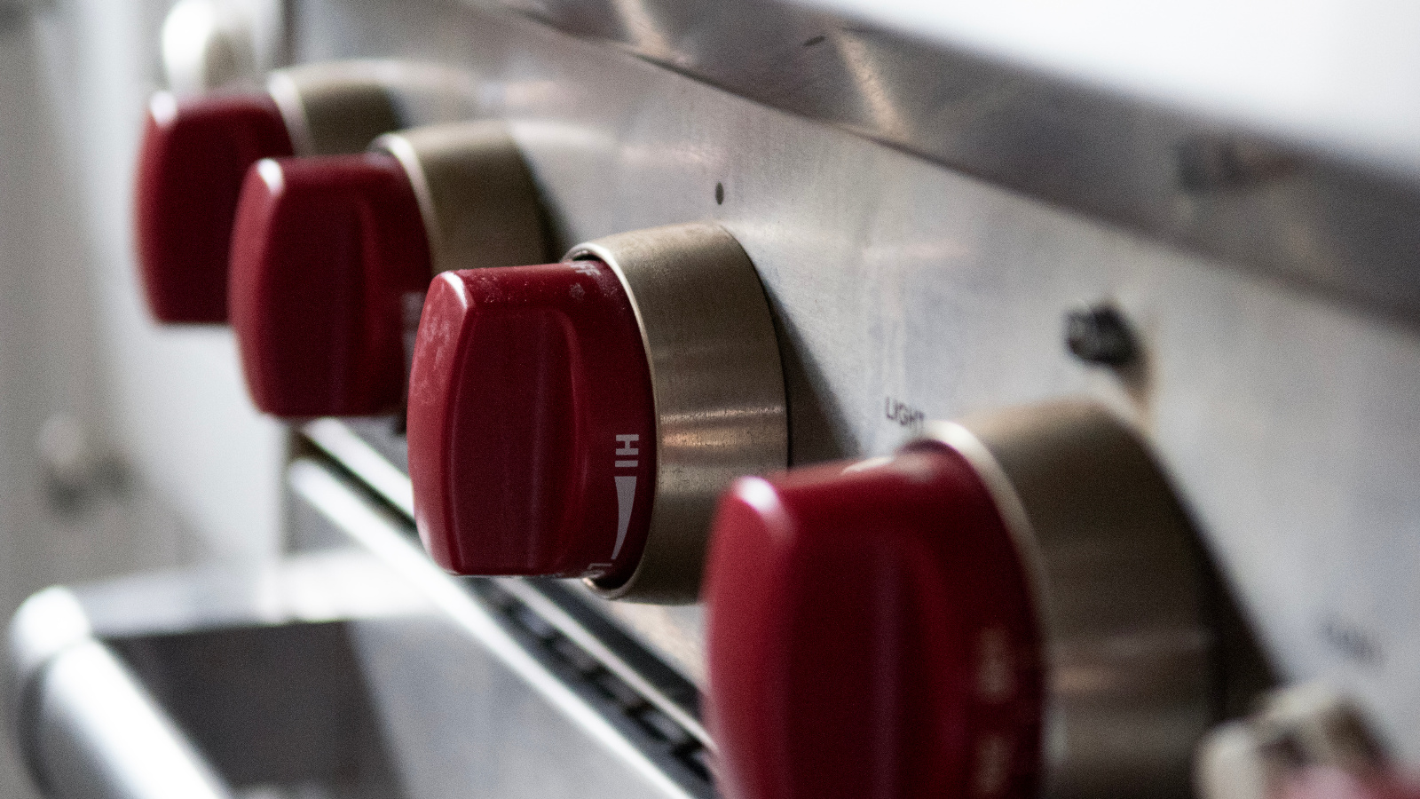 A photo of red knobs on a gas stove.