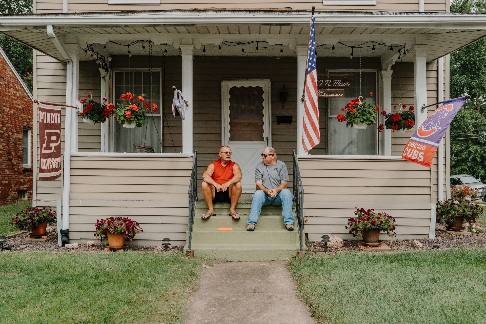 Two men sit on the front steps of a house