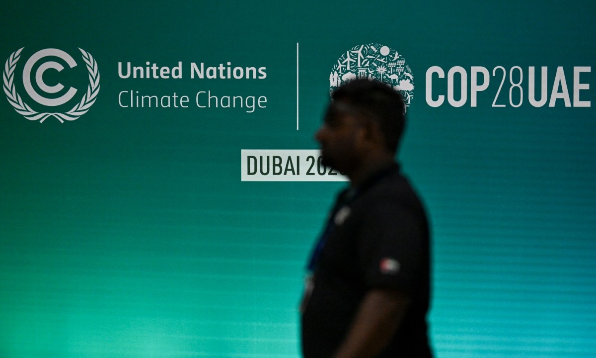 A man walks past a COP28 logo ahead of the United Nations climate summit in Dubai on November 28, 2023. The UN chief urged world leaders to take decisive action to tackle ever-worsening climate change when they gather at the COP28 summit in Dubai starting this week.