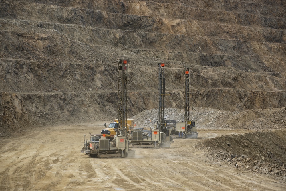 three pieces of equipment drive through a mined valley