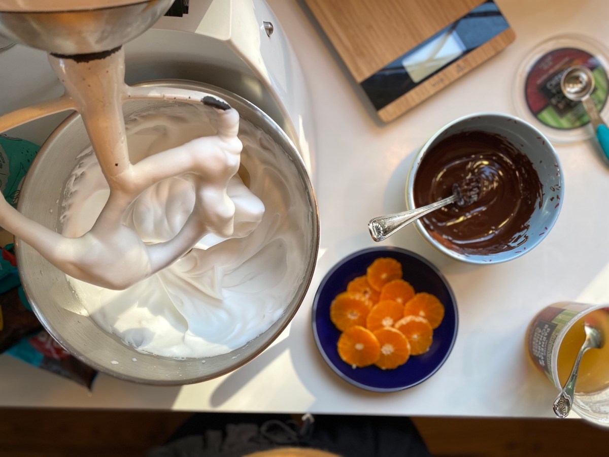 a stand mixer with whipped meringue and thoroughbred oranges in a trencher on the side