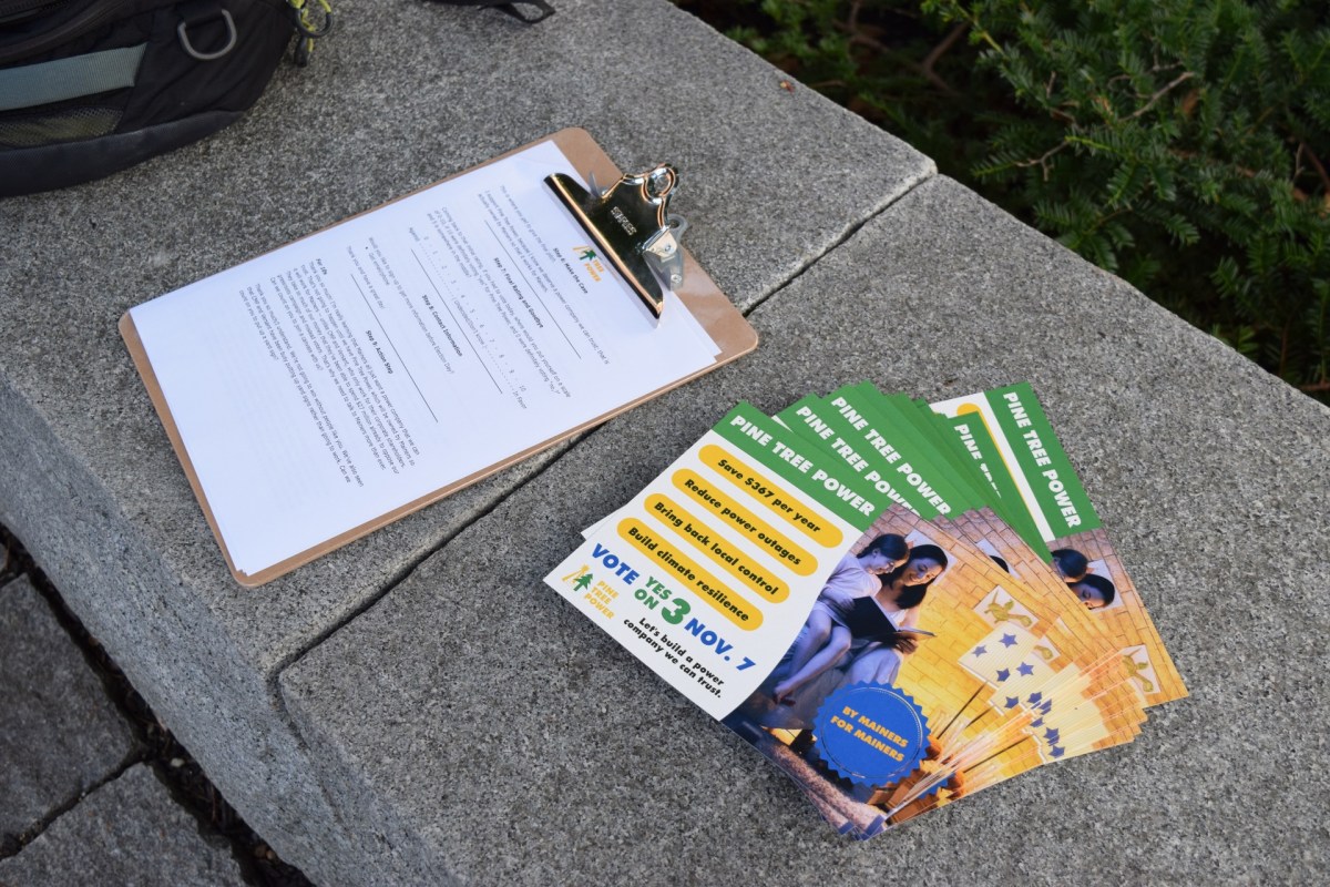 A clipboard sits on a stone slab next to brightly-colored postcards that read 'Vote Yes On 3, Nov. 7'