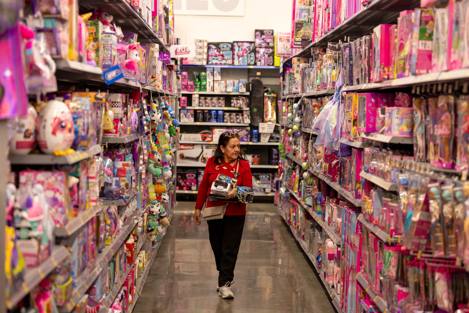 Person wearing red sweater in aisle filled with mostly pink toy boxes