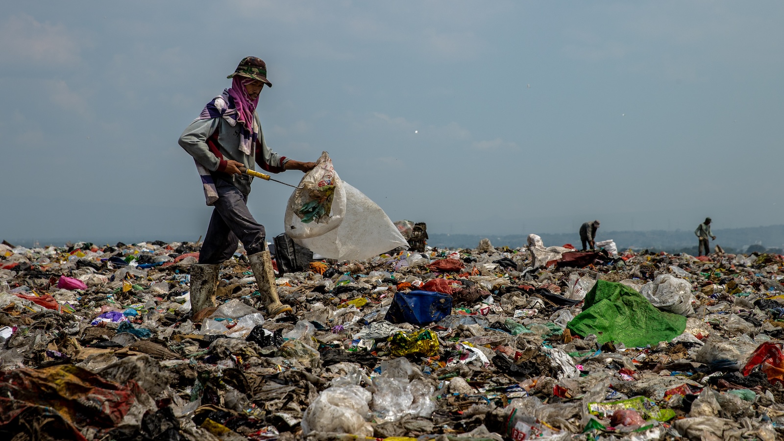 A person picks up trash in a landfill