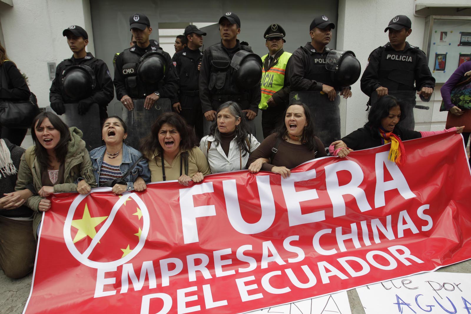 a group of people hold a red sign that says Fuera Empresas Chinas del Ecuador