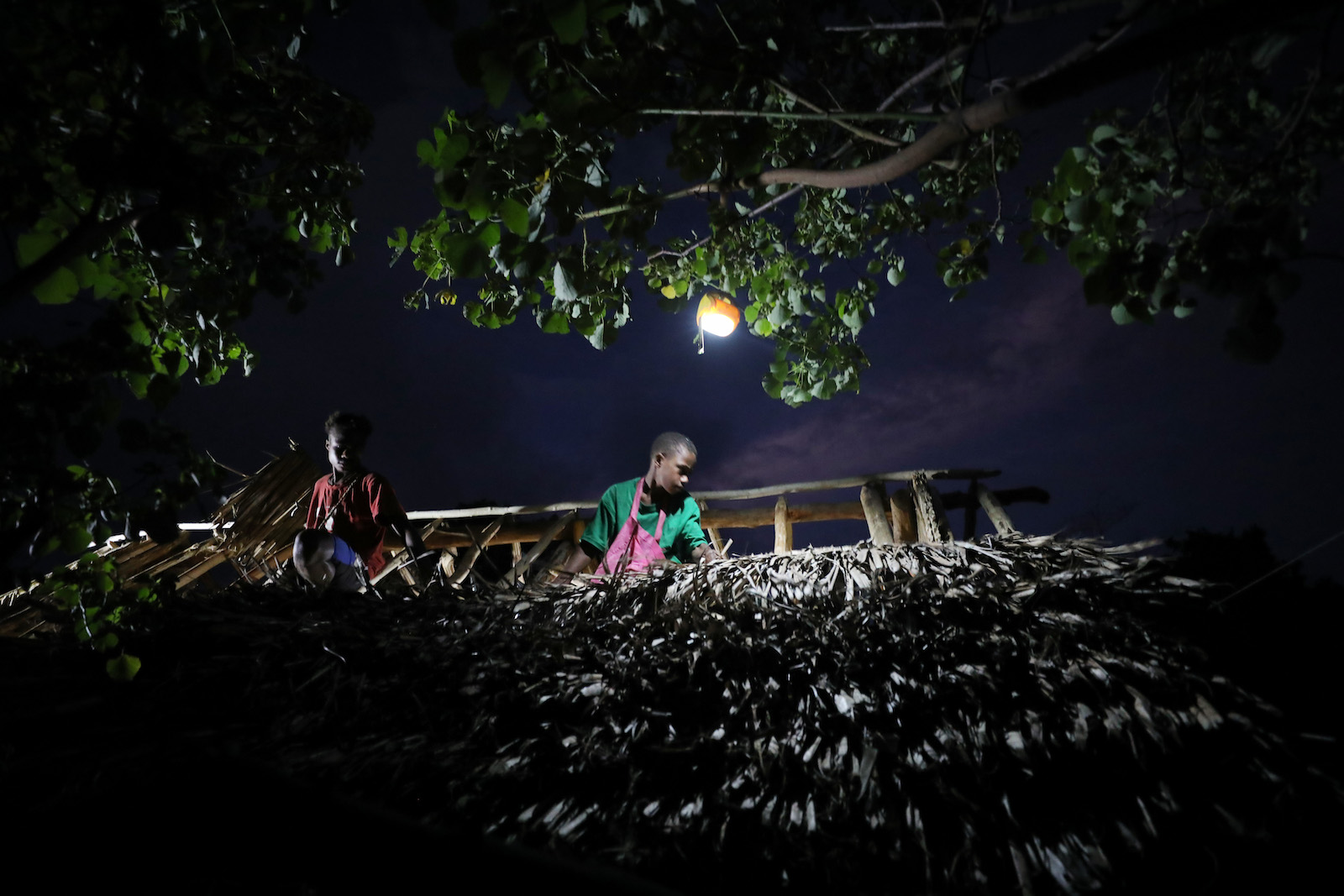 people work on a roof in the moonlight