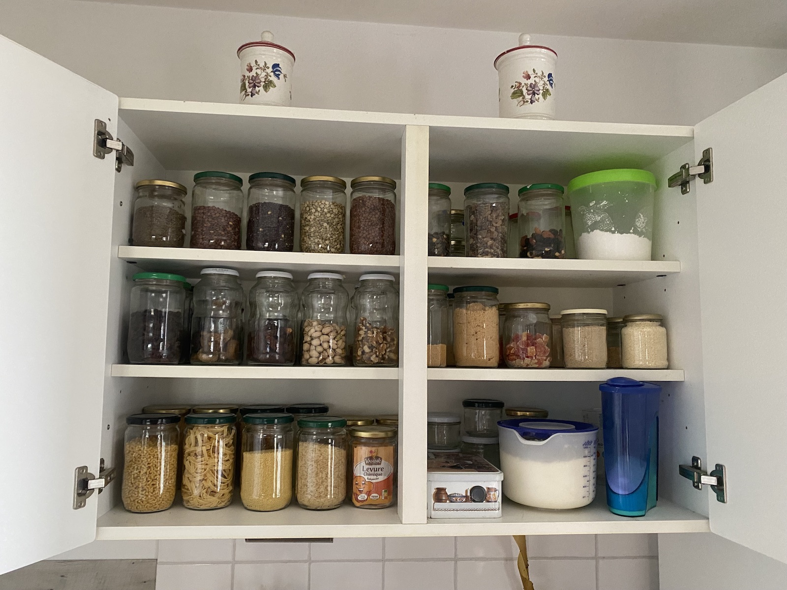 A cabinet full of many mason jars of dry foods