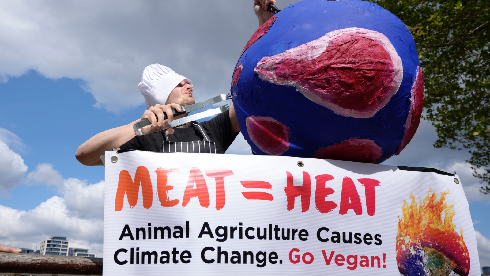 A protester dressed a butcher stabs a model of Earth as part of a demonstration calling on people to go vegan