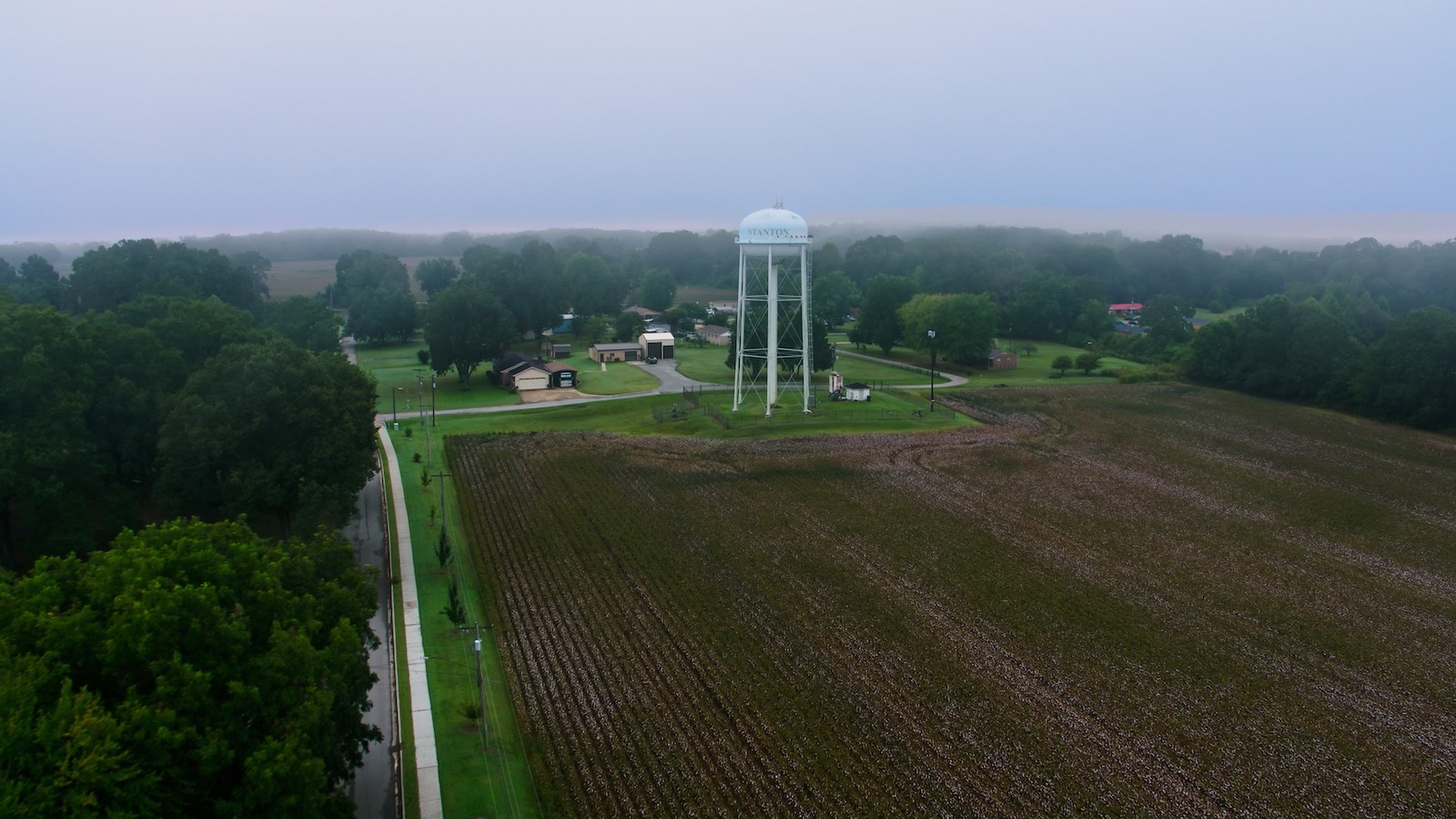 A plowed field and water tower are shouded in fog in an aerial photo of the town of Stanton, Tennessee.