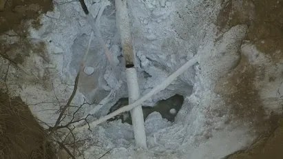 A closeup of a broken pipe in a hole.