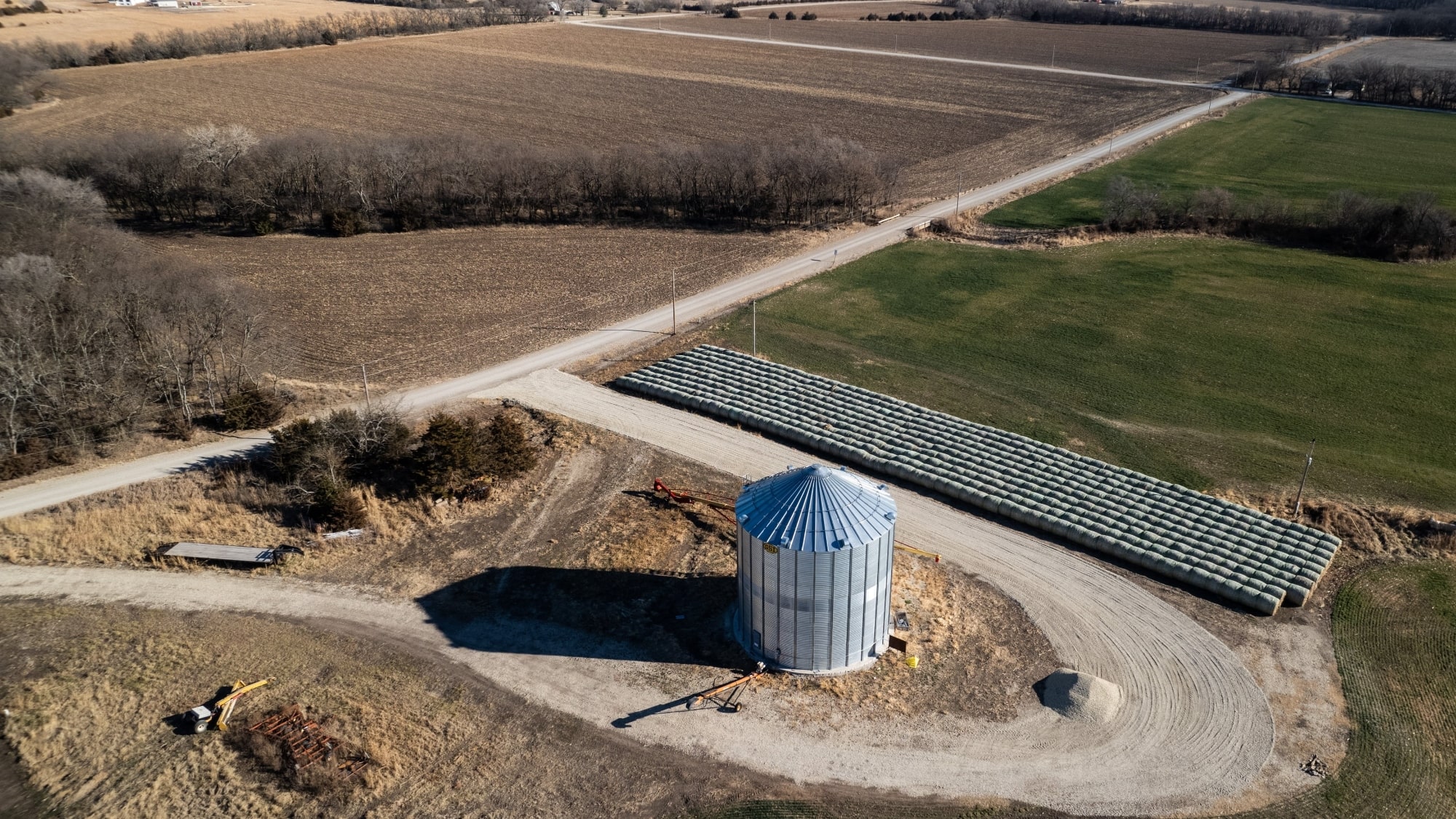 An overhead shot of a grain silo set on a farm with rolling fields.
