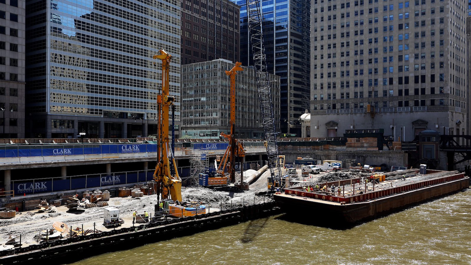Barges and cranes on Chicago river working on buildings.