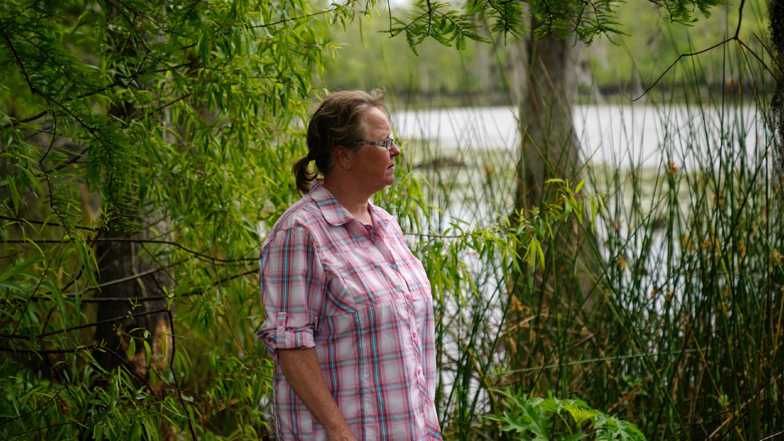A concerned resident stands by a river near Lake Maurepas in Louisiana, where she worries about the environmental impacts of new carbon capture projects.