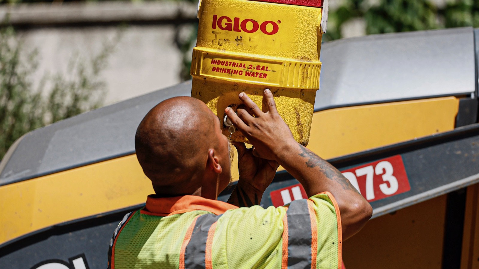 A construction worker in Los Angeles takes a break from repaving a road to drink directly from a water cooler as temperatures top 100 degrees.