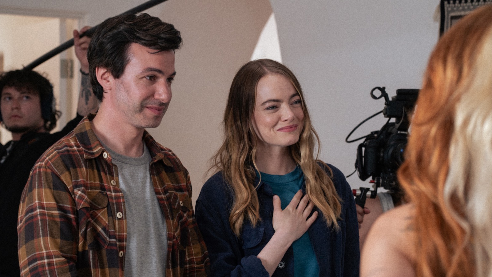 Nathan Fielder stands next to Emma Stone, with cameras and booms surrounding them.