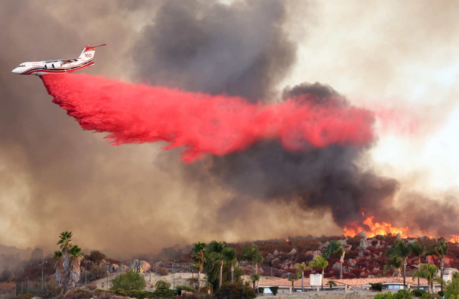 A firefighting aircraft drops fire retardant as the Fairview Fire burns near hillside homes on September 6, 2022, near Hemet, California