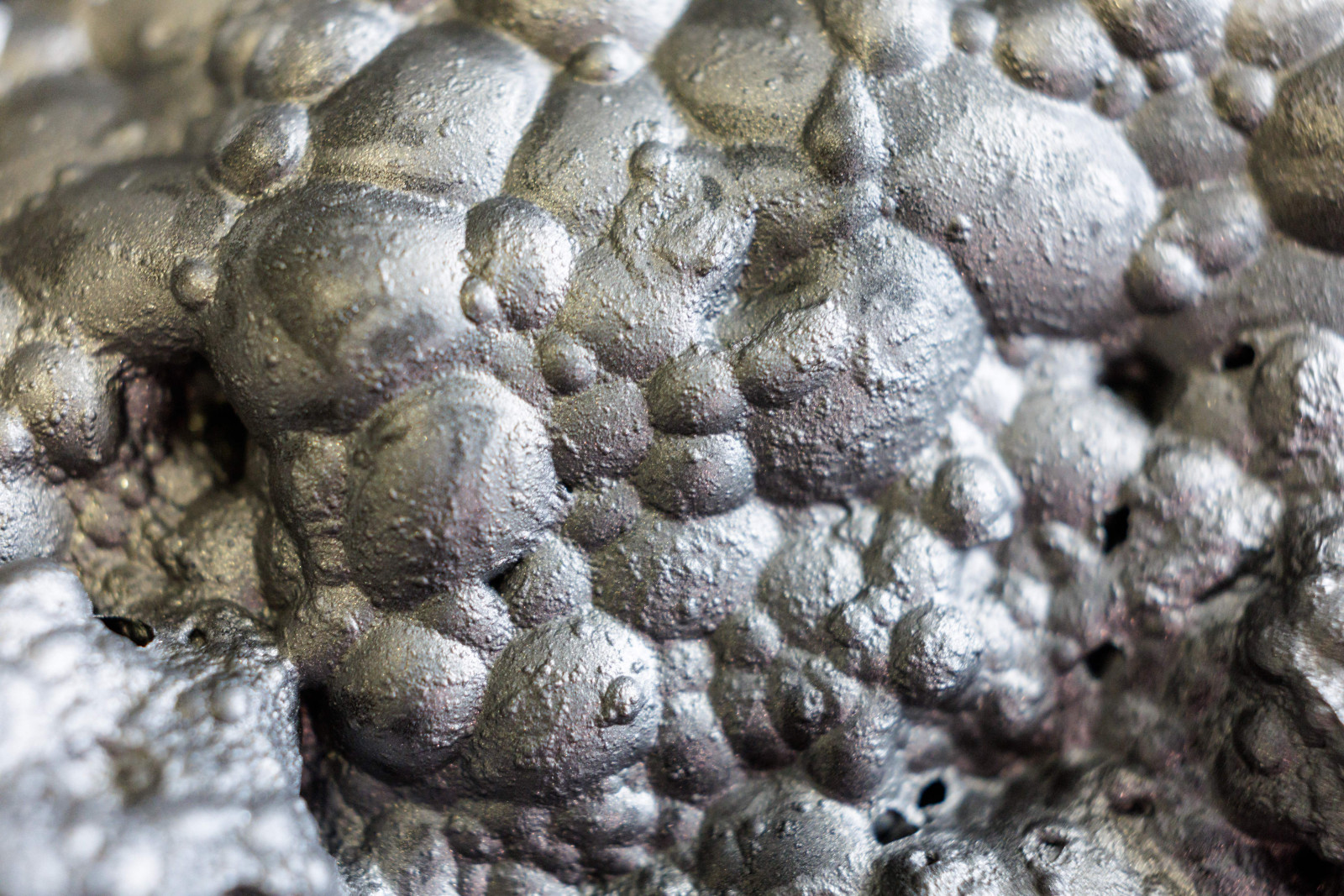 A very close-up image of air bubbles in a silvery metallic substance