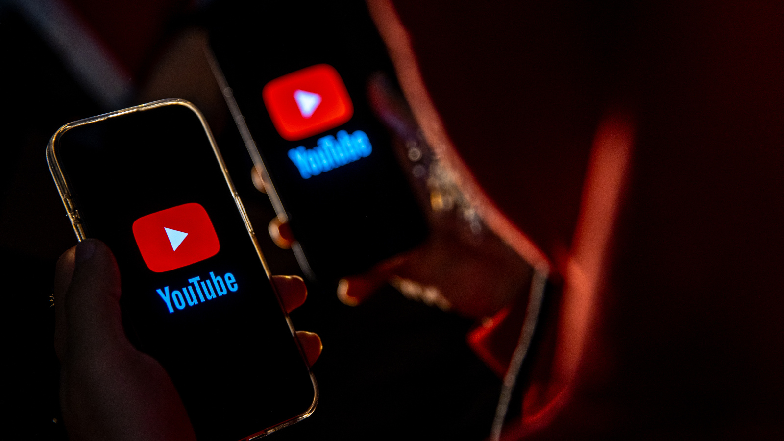 A photo illustration of the YouTube logo on mobile phone screens with a dark, ominous background.