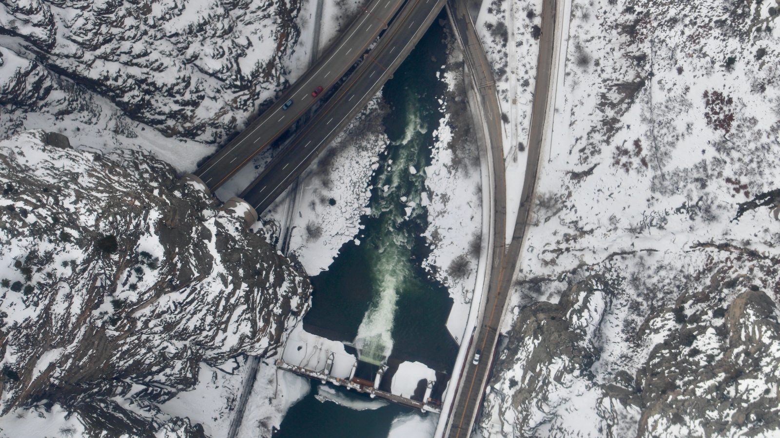 An aerial view of highways cutting through snowy land and a river running through them.