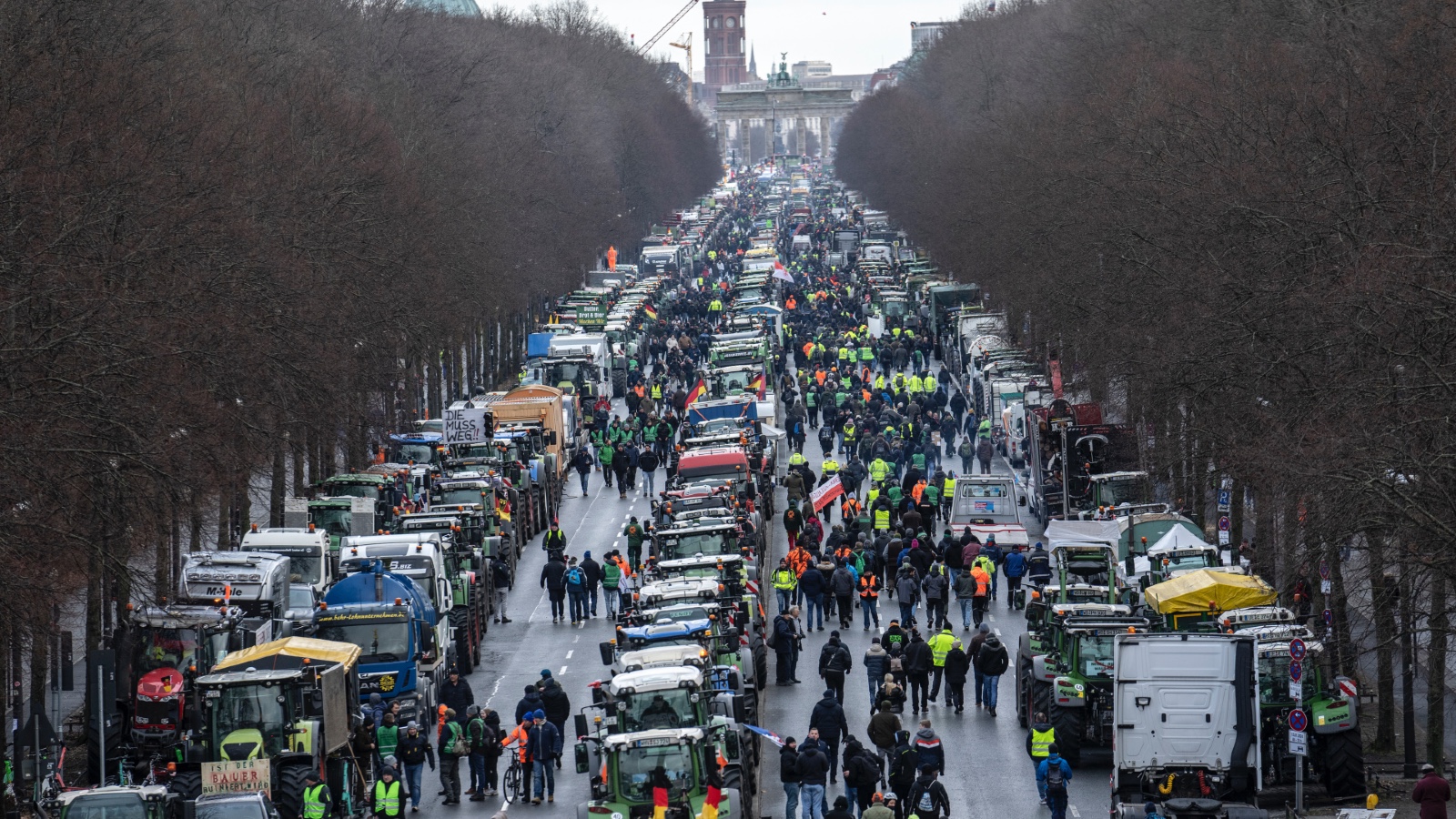 A long line of farmers and tractors blocks the boulevard leading to Brandenburg Gate in the background