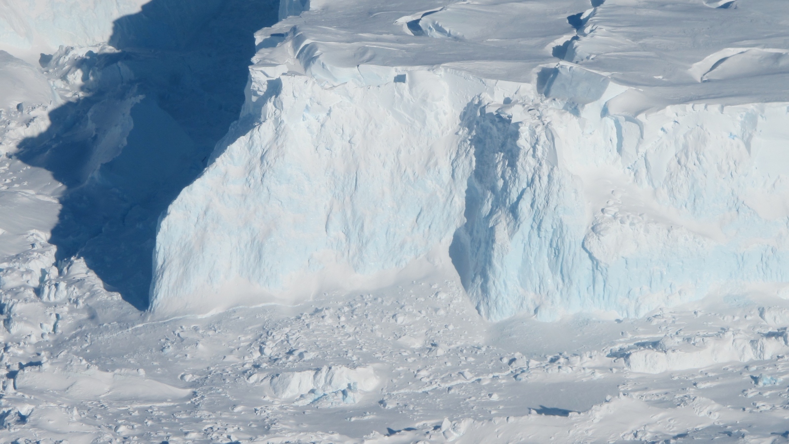 An aerial view of a massive bluish white chuck of snowy ice.