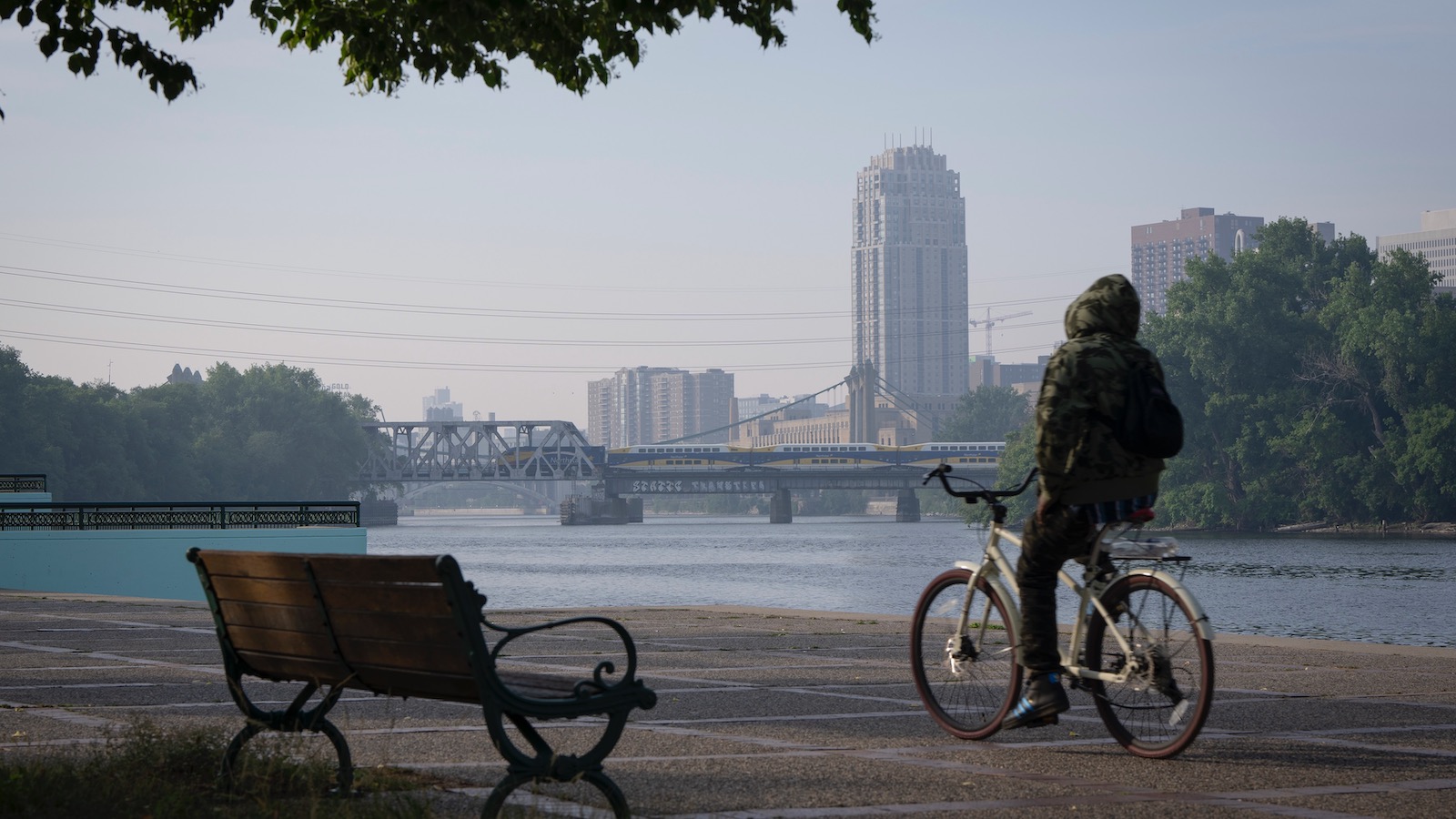 A cyclist rides along a river in Minneapolis, Minnesota, as smoke from Canadian wildfires blankets the city on June 27, 2023.
