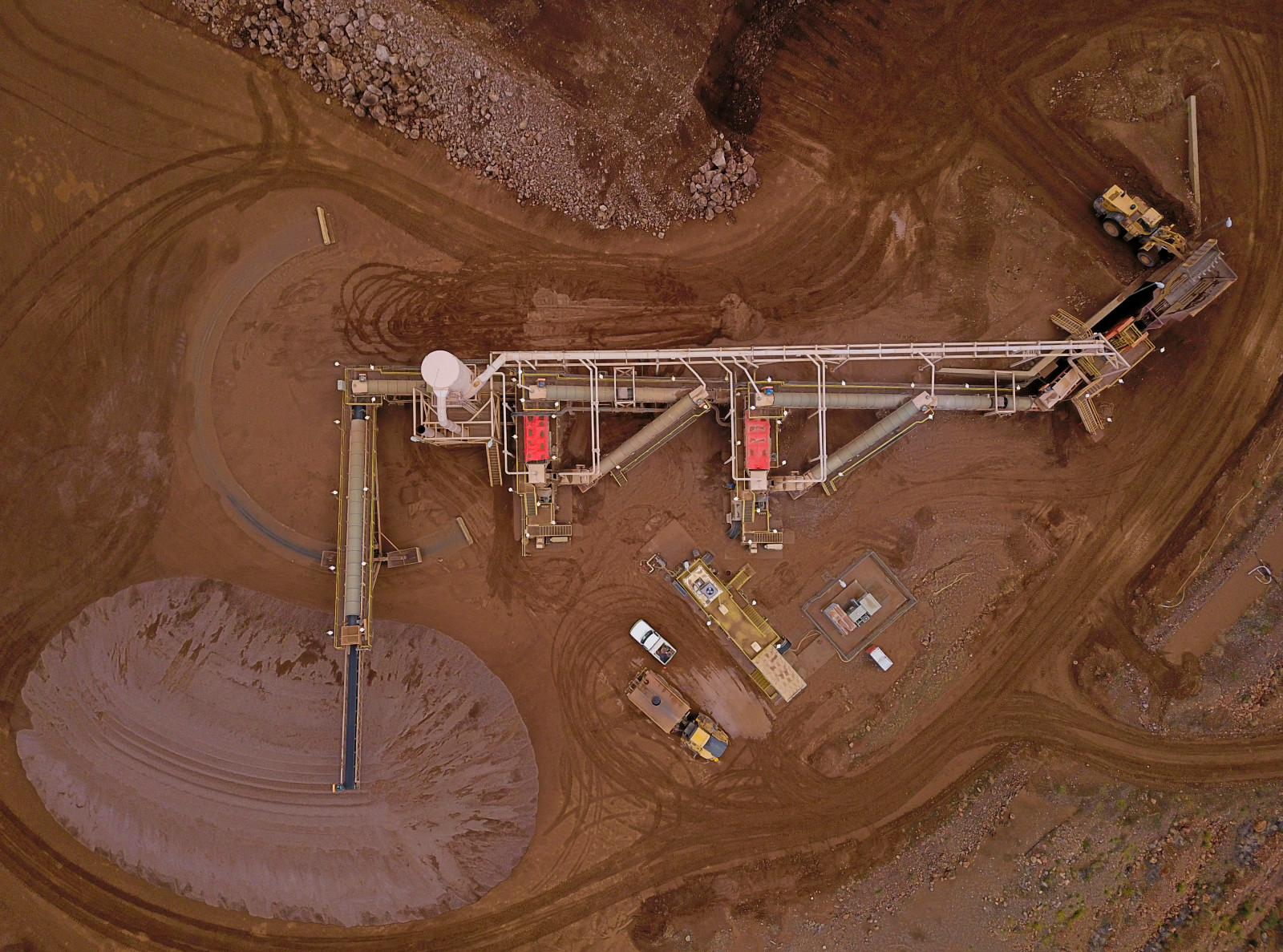 An aerial view of brown earth with mining equipment arrayed on top of it