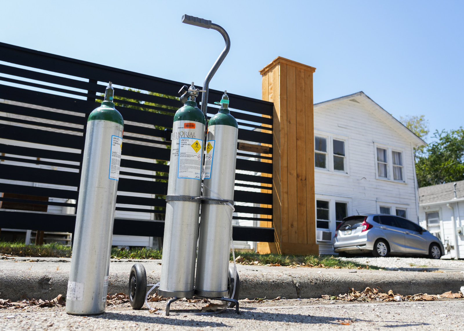 Three oxygen tanks next to a fence near a house
