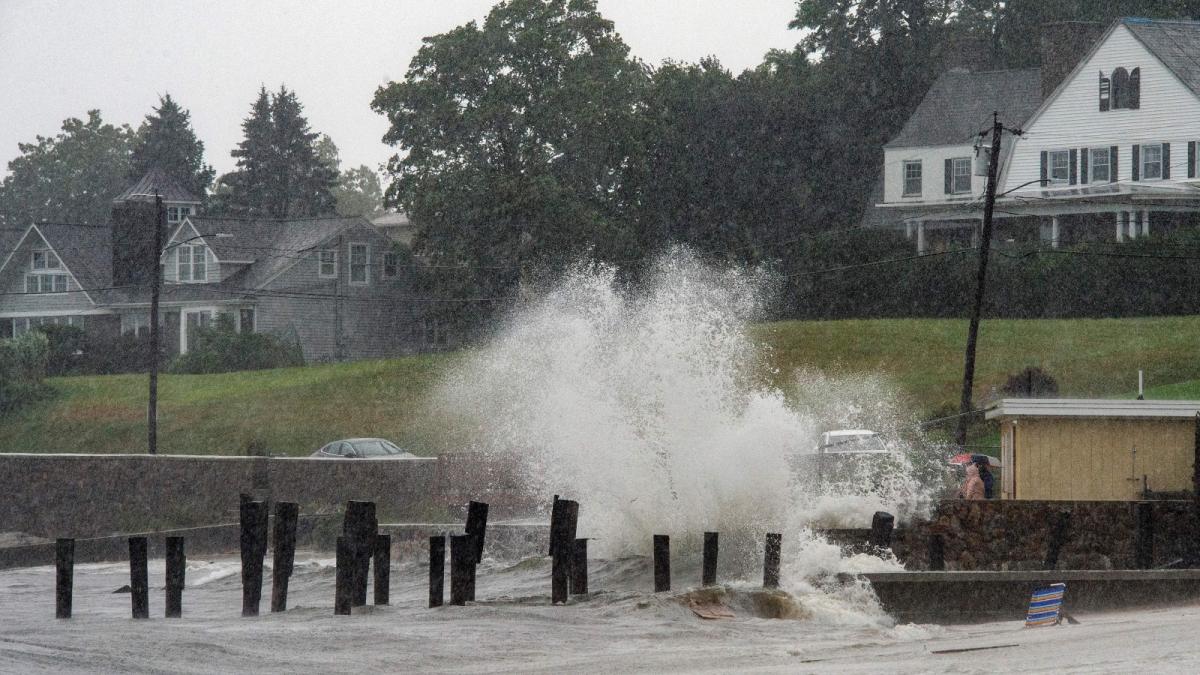 Waves crash over a broken pier as people watch from a seawall during Tropical Storm Henri in New London, Connecticut, in August of 2021.