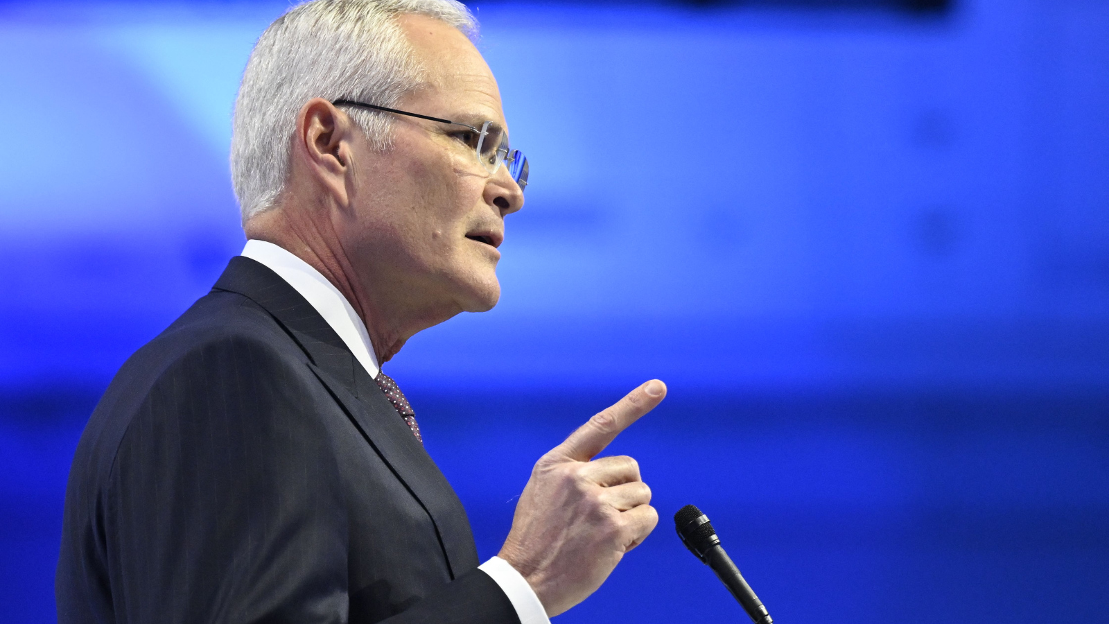 Photo of Darren Woods, Exxon CEO, pointing a finger in front of a microphone