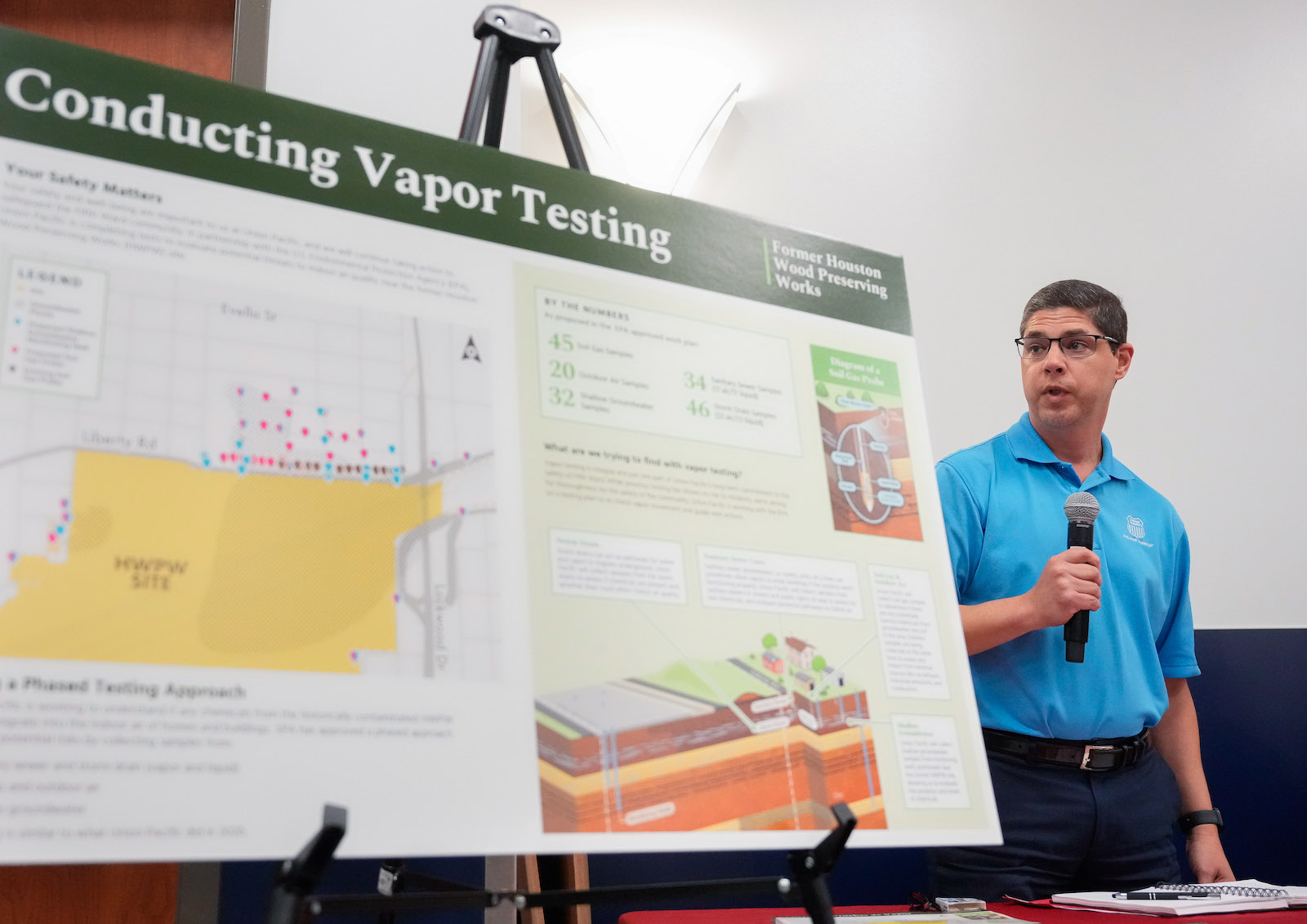 a person with a microphone talks behind a vapor testing presentation board