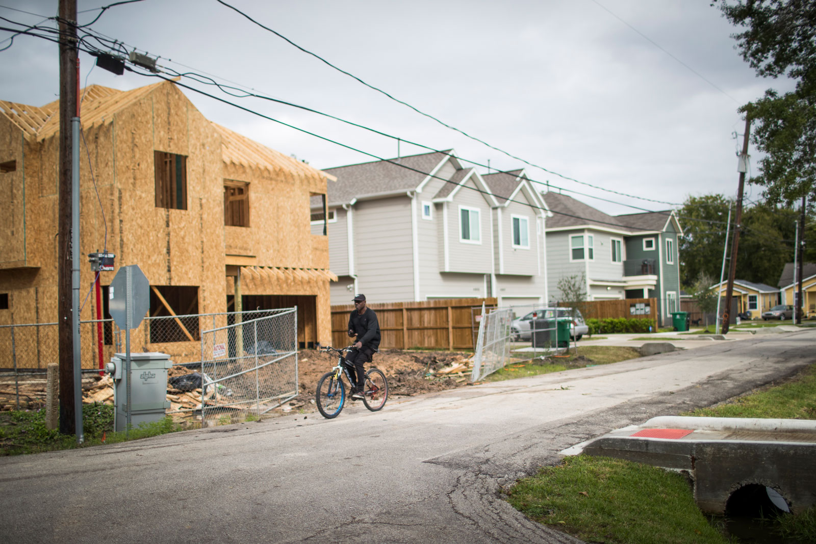 A person bikes past a row of new homes, one still under construction