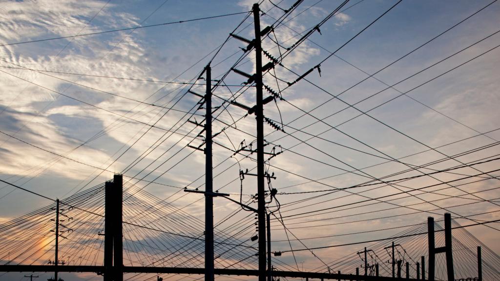 Power lines along the Savannah River at dusk form a pattern of intersecting lines with the cables of the Talmadge Memorial Bridge in the distance
