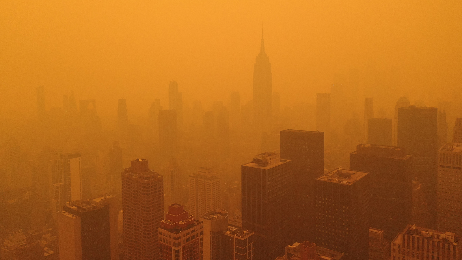 An aerial photo of oange, hazy skies over New York City.