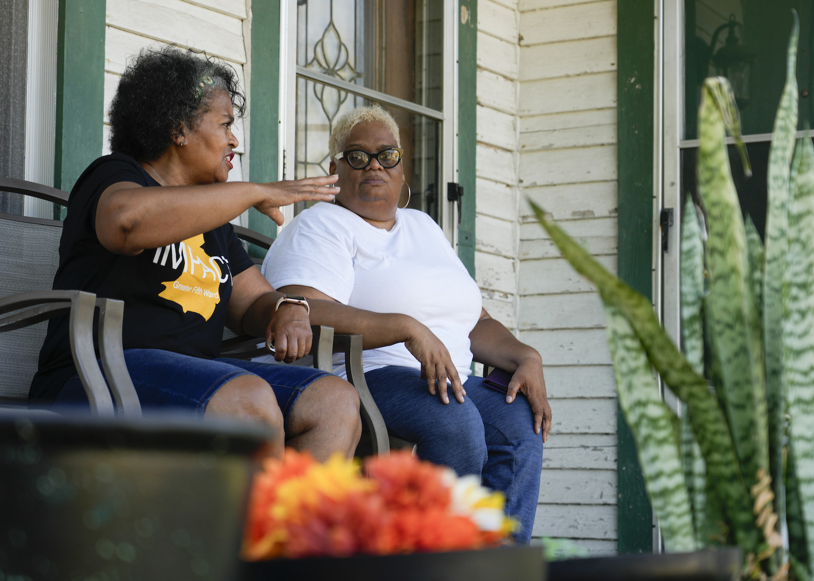 Two women sit on a porch talking