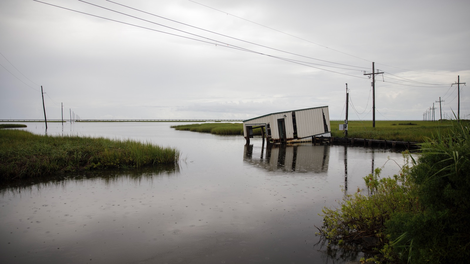 A small covered fishing dock dips into coastal waters near Bayou Lafourche in Leeville, Louisiana