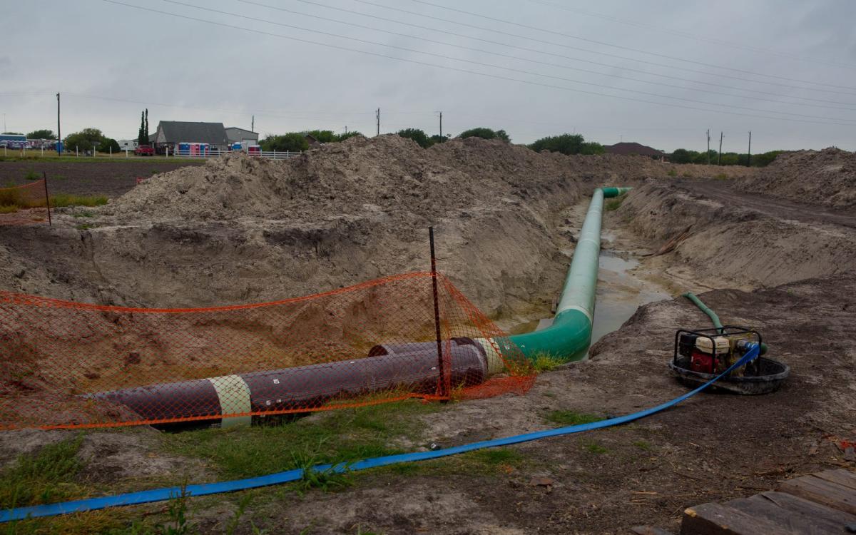 A plastic tube runs along a ditch in a construction site