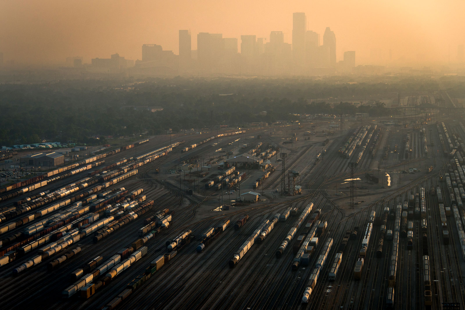 An aerial view of a rail yard with the Houston skyline in the distance