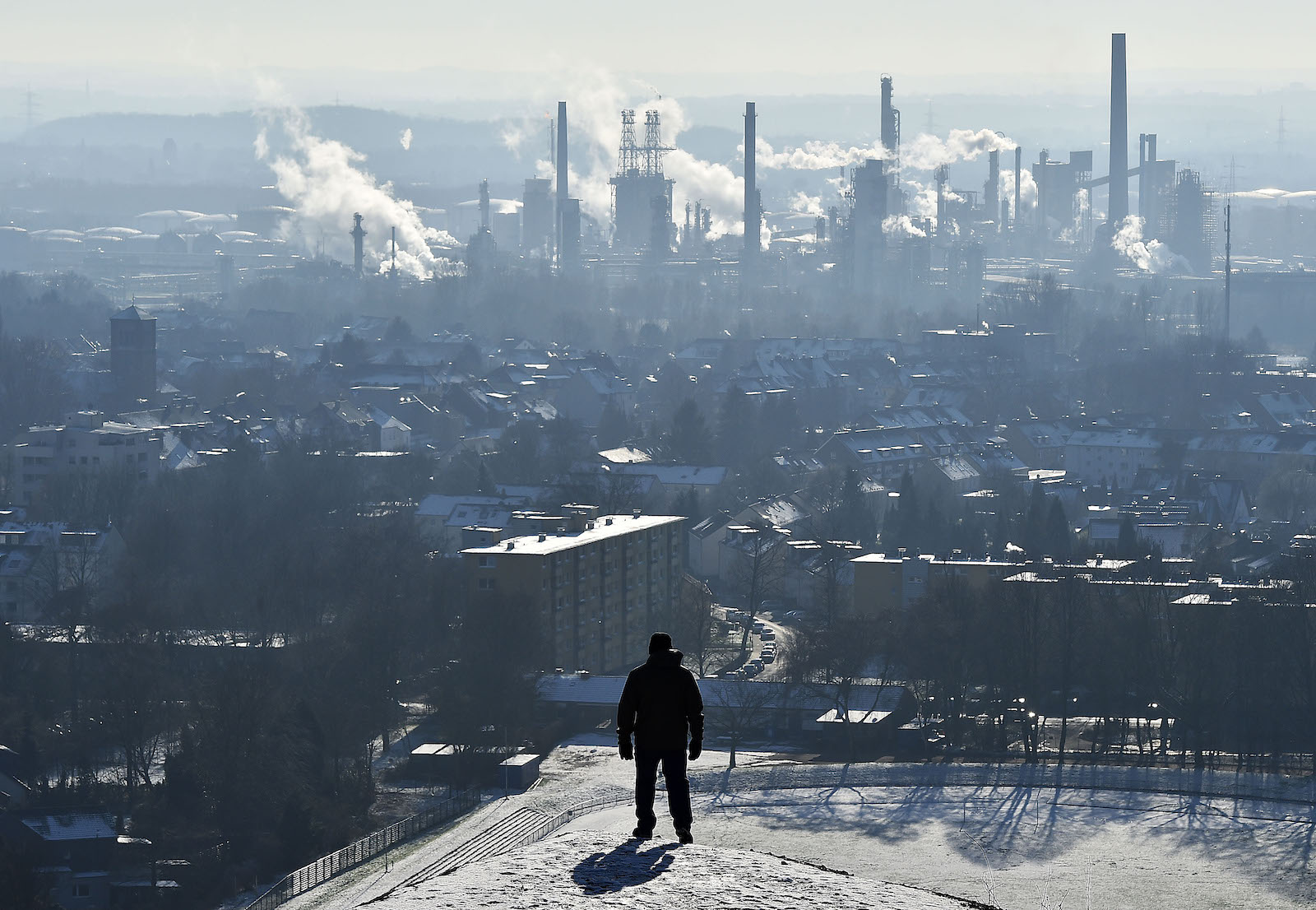 Man looks at refinery in distance