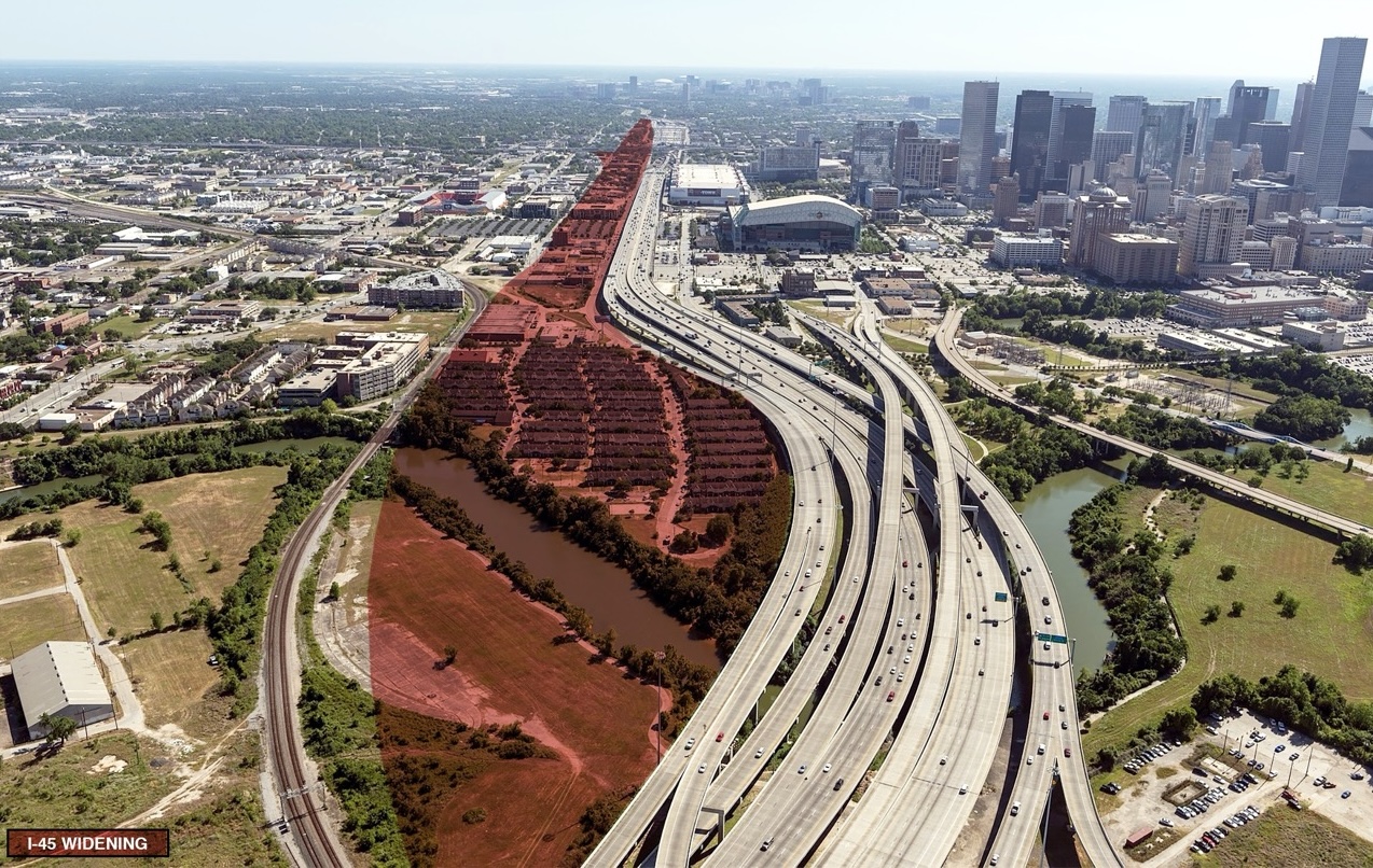 An aerial view of a knot of highways next to a city, with an area next to the highways highlighted red.
