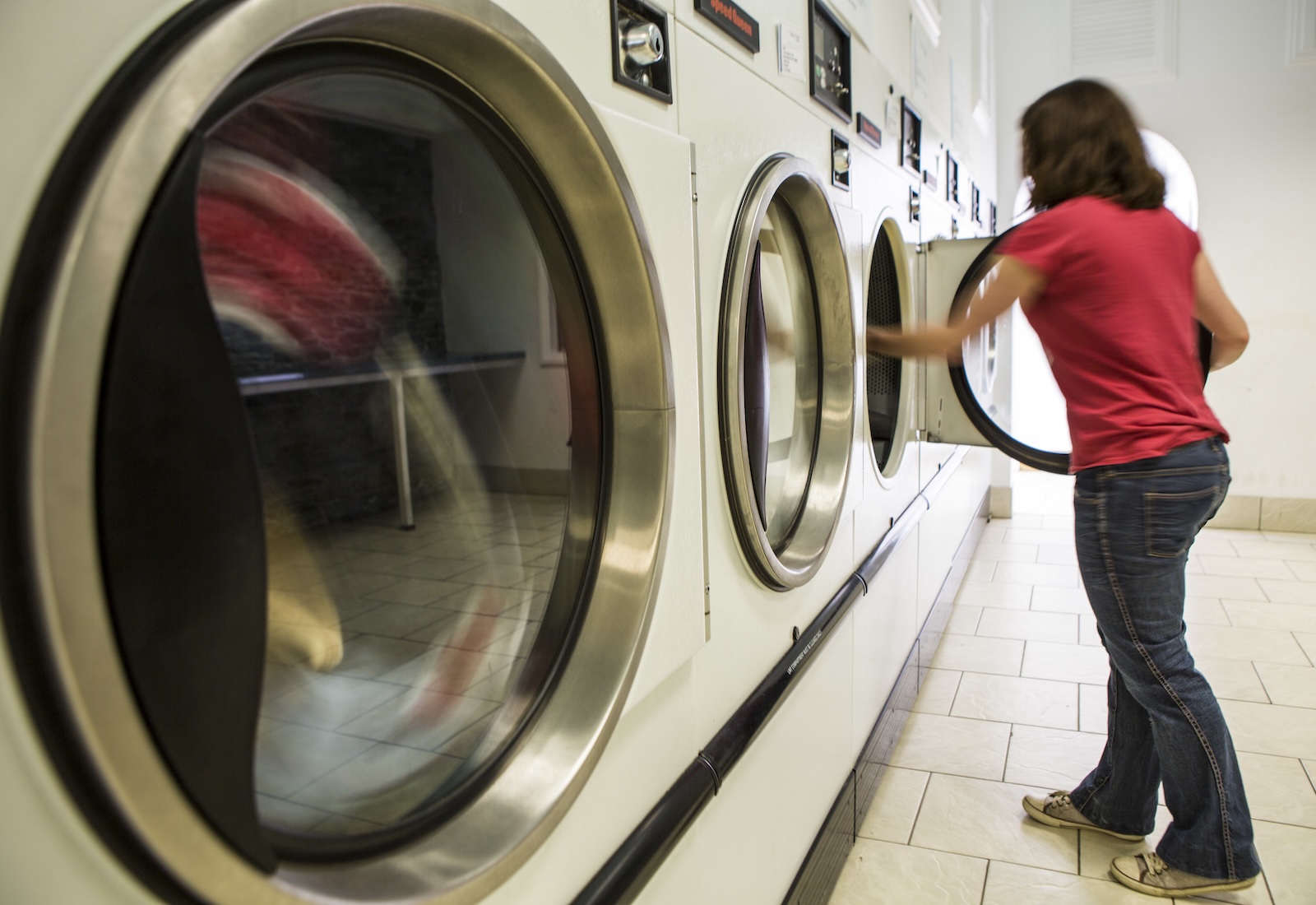 Woman removes laundry from a washing machine.