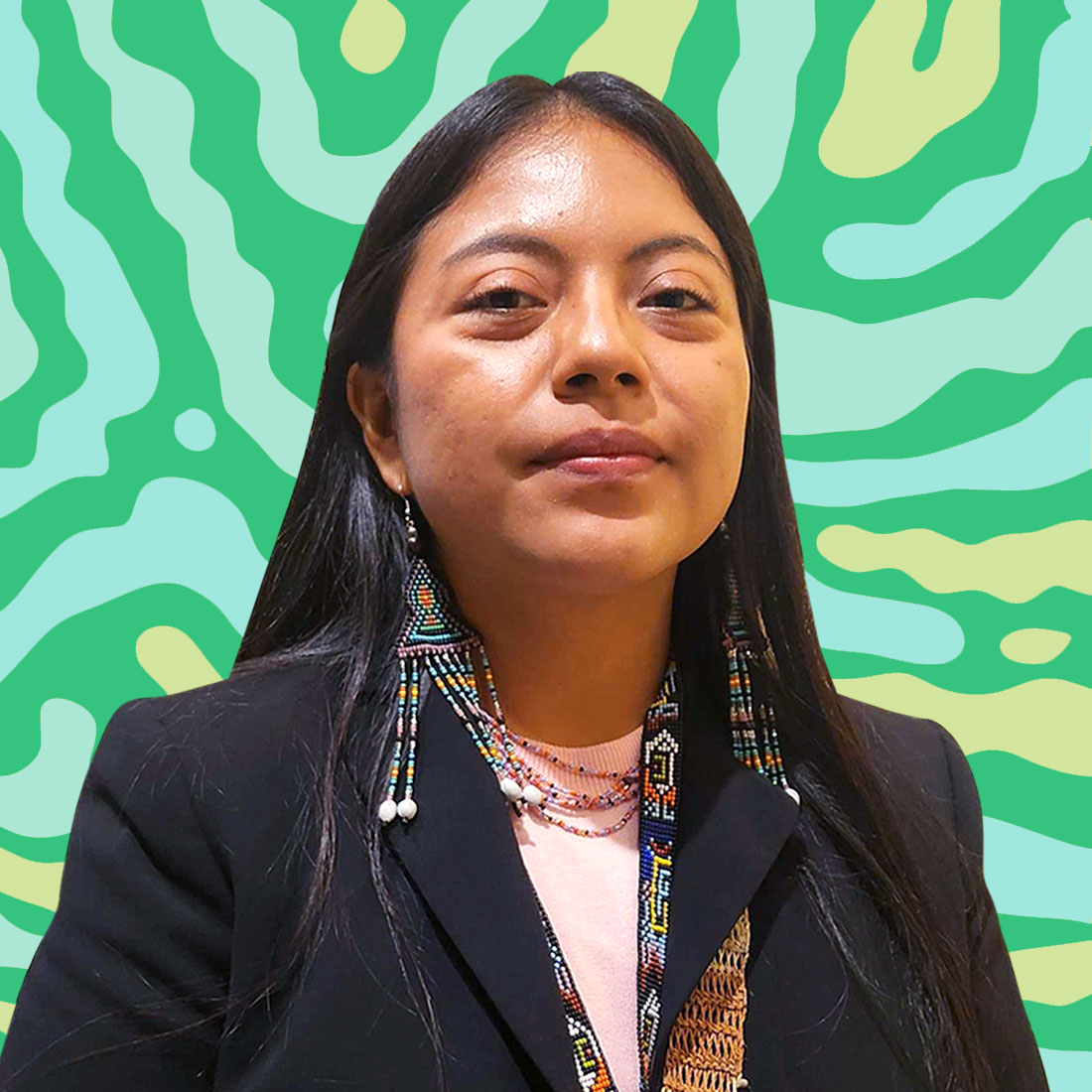 A headshot of a young person in a black jacket and wearing beaded earrings on a green and yellow striped background