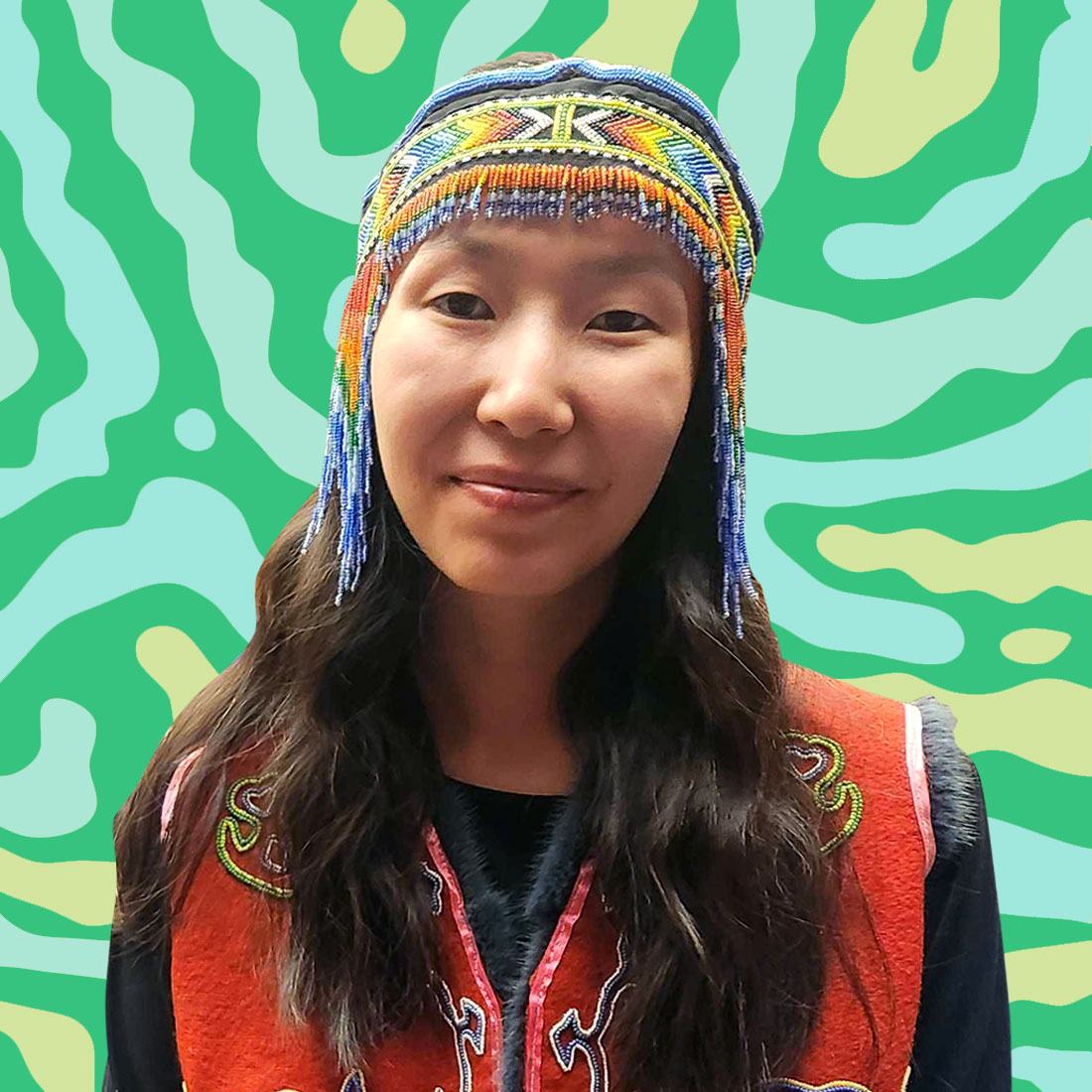 A headshot of a young person with a beaded headdress on a green and yellow striped background