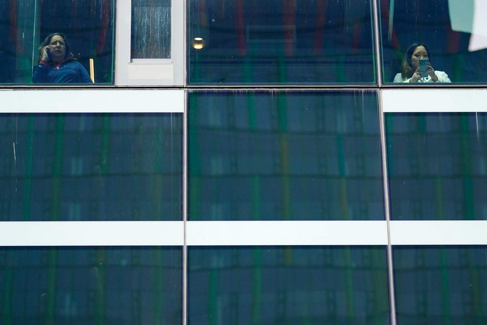 オフィスビルと窓の外を眺める2人の写真
