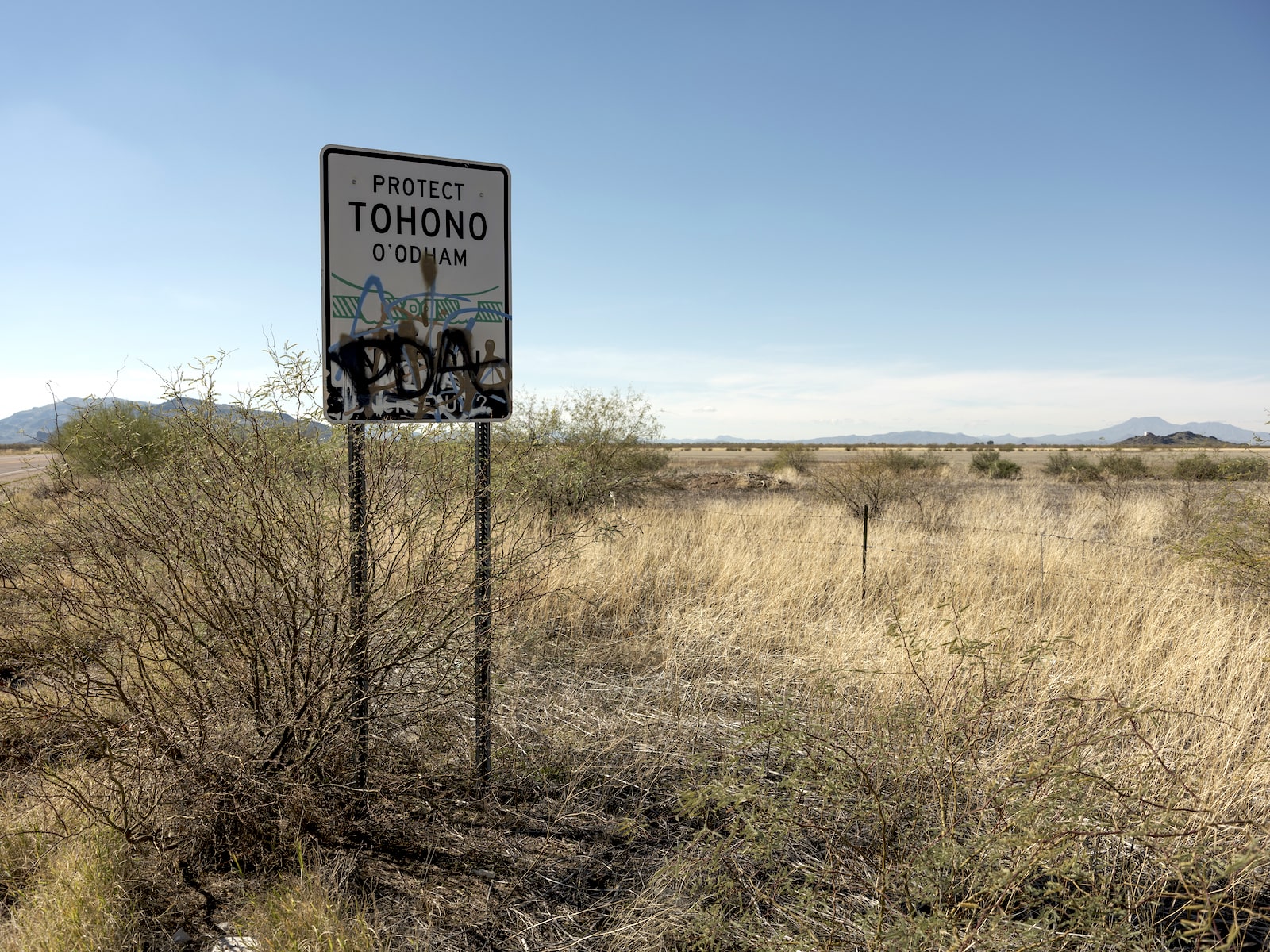 A sign with graffiti says protect Tohono O'odham