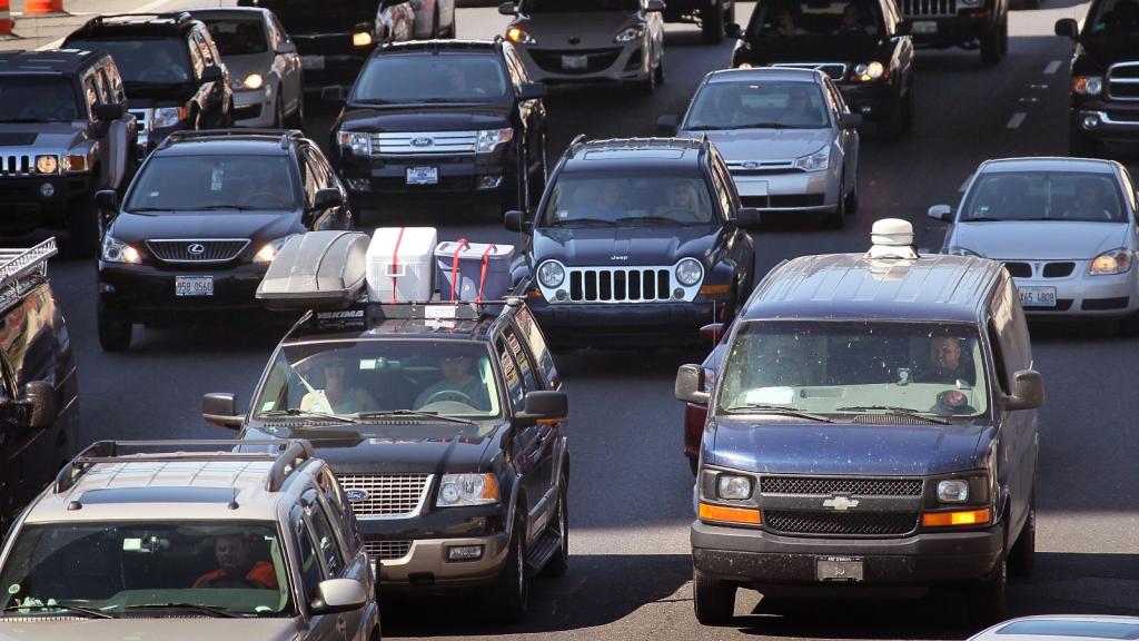 Cars sit in bumper to bumper traffic on a highway.