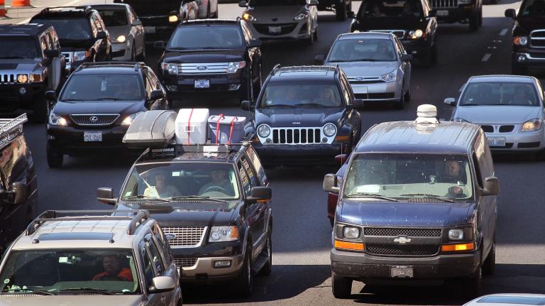 Cars sit in bumper to bumper traffic on a highway.